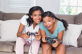 Happy mother and daughter playing video games together on sofa