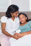 Concerned mother cuddling sick daughter