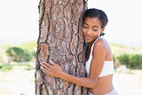 Fit woman hugging a tree