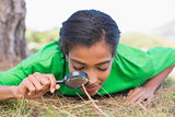 Pretty environmental activist looking at grass through magnifying glass