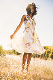 Happy pretty woman standing on the grass in floral dress