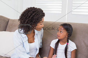 Pretty mother sitting on the couch scolding her daughter