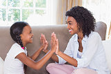 Pretty mother playing clapping game with daughter on couch