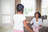 Pretty mother sitting with open arms for daughter on sofa