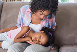 Cute daughter sleeping across mothers lap on the sofa