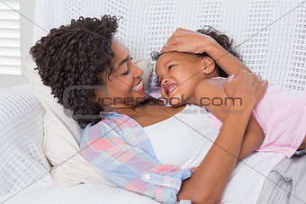 Cute daughter lying with mother on the sofa