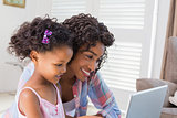 Cute daughter using laptop at desk with mother