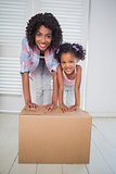 Cute daughter unpacking moving boxes with her mother