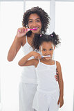Pretty mother with her daughter brushing their teeth