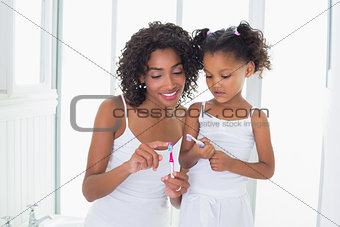 Pretty mother showing her daughter her toothbrush