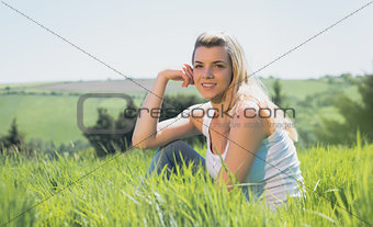 Pretty blonde smiling at camera sitting on grass