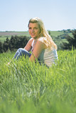 Pretty blonde smiling at camera sitting on grass