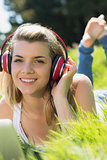Pretty blonde lying on grass using laptop listening to music