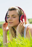 Pretty blonde lying on grass listening to music