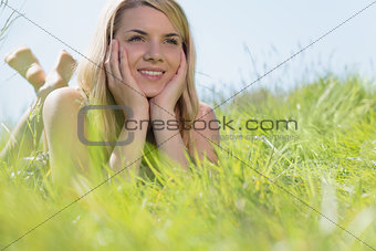 Pretty blonde in sundress lying on grass smiling