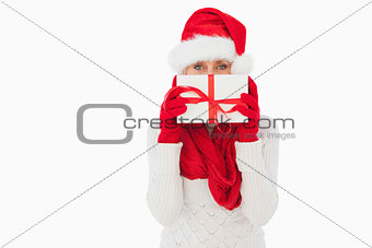 Festive woman looking at camera holding a gift