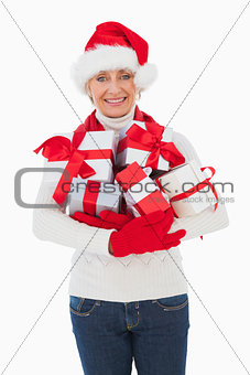 Festive woman smiling at camera holding gifts
