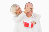Older woman covering her partners eye while holding present