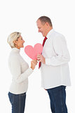Older affectionate couple holding pink heart shape