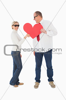 Older affectionate couple holding red heart shape