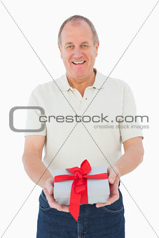 Mature man smiling at camera holding gift