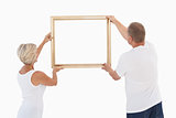 Mature couple hanging up picture frame