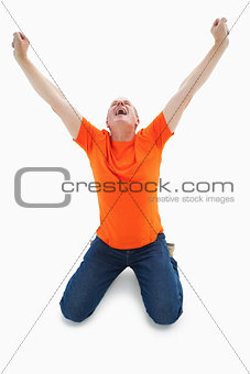 Mature man in orange tshirt cheering while kneeling