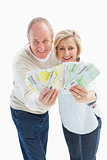 Happy mature couple smiling at camera showing money
