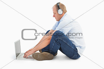 Mature man using laptop listening to music