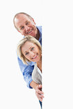Mature couple smiling behind wall