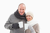 Happy mature couple in winter clothes holding mugs