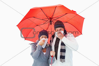 Mature couple blowing their noses under umbrella