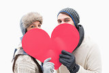 Attractive young couple in warm clothes holding red heart