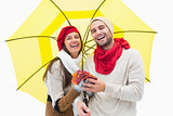 Attractive young couple in warm clothes holding umbrella and leaves