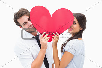 Couple smiling at camera holding a heart