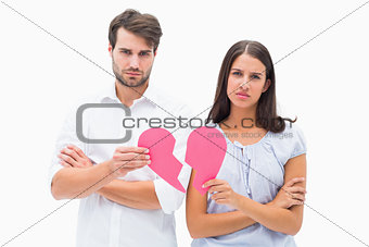 Upset couple holding two halves of broken heart