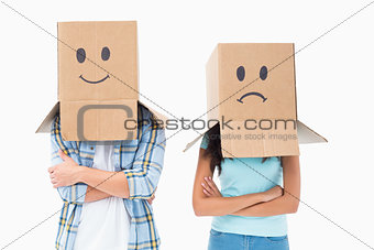 Young couple wearing sad face boxes over head