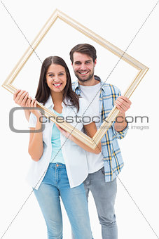 Happy young couple holding picture frame
