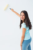 Happy young brunette painting with roller