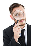 Geeky businessman looking through magnifying glass