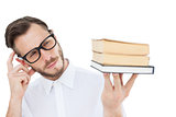 Geeky young man looking at pile of books