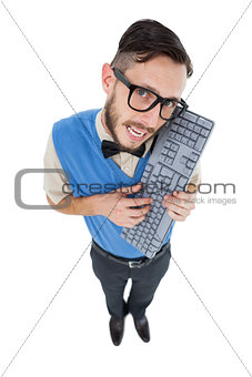 Geeky hipster looking at camera holding keyboard