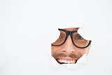 Geeky hipster looking at camera through hole