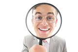 Geeky businessman looking through magnifying glass