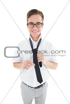Geeky hipster fixing his tie smiling at camera