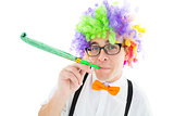 Geeky hipster wearing a rainbow wig blowing party horn