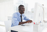 Happy businessman working at his desk wearing headset