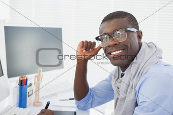 Hipster businessman smiling at camera at his desk