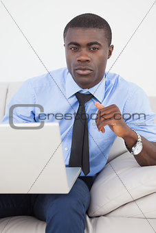 Handsome businessman using laptop on sofa