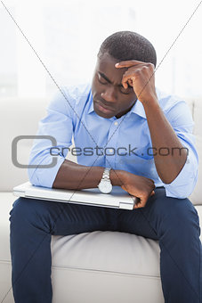 Stressed businessman getting a headache holding his laptop